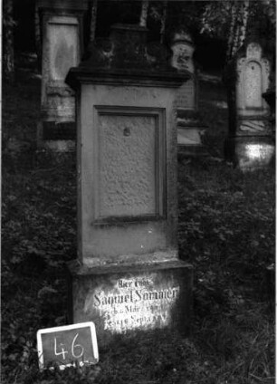 Grabstein 46 (Index: 100101025) Material: Sandstein Zustand: Schrifttafel fehlt, Sockel verwittert Maße HxBxT: 155x46x20 cm Beschreibung: Stele, Sockel, Abdeckplatte mit rechteckigem Aufsatz und seitlichen Voluten, Flammenaufsatz Symbolik: Voluten Besonderheit: eingemeißelte Nummer: 33: Grabstein 46