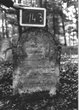 Grabstein 143 (Index: 99894882) Material: Sandstein Zustand: verwittert Maße HxBxT: 80x49x9 cm Beschreibung: Stele mit eingezogenem Rundbogenabschluss: Grabstein 143