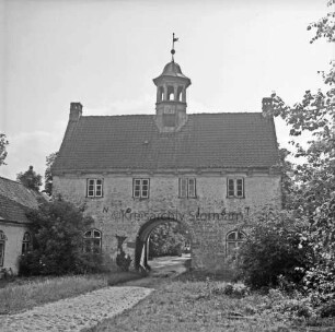 Gut Jersbek: Torhaus: Blick von Westen: links Flügelbau: davor und rechts Gesträuch und Bäume: vorn links Zufahrt