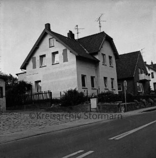 Stadtvilla: davor Vorgarten, Zaun, Stromverteilerkasten, Verkehrsschild: hinten Wohnhäuser: vorn Straße