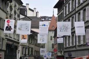 Lausanne - Werbeplakate : Am Marktplatz hängen über der Straße Plakate einer Karikaturenausstellung. Aufgenommen in Lausanne am 19. Mai 2010
