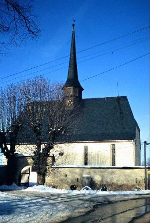 Südansicht der Kirche, die von einer Wehrmauer umgeben ist; im Torbogen Jahreszahl 1520