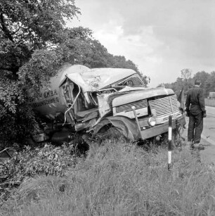 A1: Verkehrsunfall: Tanklastzug fährt in Straßengraben: Unfall-Lastzug schräg in Graben bei Baum: rechts Straße, an Straßenrand Mann von Abschleppunternehmen, Straßenpfosten