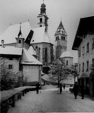 Kitzbühel in Tirol. Wintermorgen. Ansicht der verschneiten römisch-katholischen Stadtpfarrkirche "Zum Heiligen Andreas". Rechts daneben die gotische Liebfrauenkirche, deren Turm als Wahrzeichen der Stadt gilt