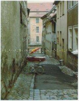Kinderwagen steht in einer engen Gasse (Altersgruppe 18-21)