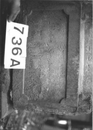 Grabstein 736 (Index: 99900422) Material: Sandstein Zustand: fast völlig verwittert Maße HxBxT: 165x54x20 cm Beschreibung: aufgesockelte Stele mit eingezogenem Dreiecksabschluss, Giebel- und Eckakroterien, im Giebel Levitenkanne, Inschrift von Säulen gerahmt Symbolik: Levitenkanne: Grabstein 736A