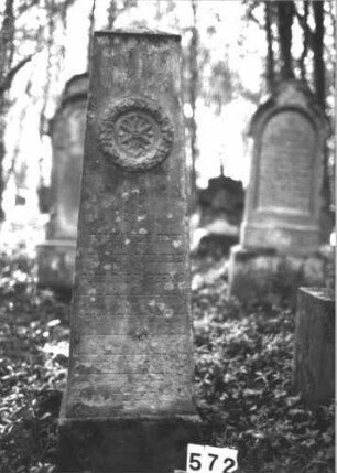 Grabstein 572 (Index: 99898152) Material: Sandstein Zustand: stark verwittert Maße HxBxT: 156x45x37 cm Beschreibung: Obelisk, oberhalb der Inschrift Blüte in Efeukranz Symbolik: Efeukranz, Blüte Besonderheit: Kindergrab: Grabstein 572