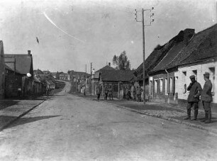Prémont / Nordfrankreich [mehrere Soldaten vor Wohnhäusern in einer verlassenen erscheinenden Straße] (Bemerkung: Stempel auf der Rückseite: S.B. Reserve-Infanterie-Regiment 56 3. Kompanie)
