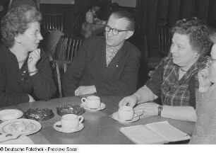 Drei Frauen und ein Mann beim Kaffeetrinken