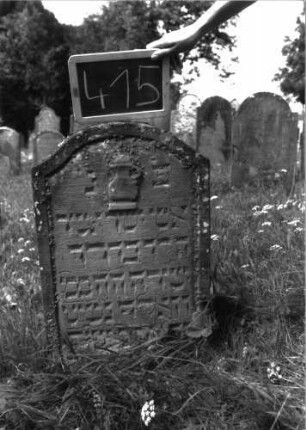 Grabstein 415 (Index: 100102792) Material: Sandstein Zustand: unten stark verwittert, eingesunken, teilweiser Textverlust Maße HxBxT: 72x46x10 cm Beschreibung: Stele, Konvexbogenabschluss, im Bogen plastische Levitenkanne, Schriftfeld eingetieft Symbolik: Levitenkanne: Grabstein 415