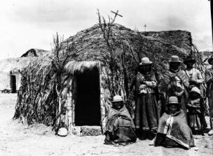 Personen neben einer Hütte : Angehörige der Aymara neben einer Hütte mit Kreuz auf dem Dach
