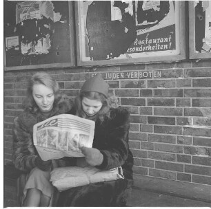 Berlin. Zwei junge Frauen beim Zeitungslesen vor der Aufschrift "Für Juden verboten"