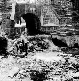 Brücke des Mühlenredder über dem Abfluss des Schlossgrabens: Seitenansicht von Norden: Jungen beim Angeln unterhalb von Wehr: durch Brückenbogen Blick auf Schlossbrücke: oben Geländer