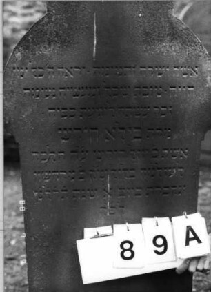 Grabstein 89 (Index: 100094790) Material: Sandstein Zustand: unten abgeblättert Maße HxBxT: 136x58x11 cm Beschreibung: Stele, Sockel, ausgezogener doppelter Rundbogenabschluß: Grabstein 89A