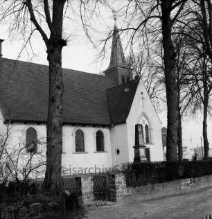 Matthias-Claudius-Kirche: Kirchsteig: Südseite: davor Ehrenmal: im Vordergrund Mauer und Pforte zum Kirchhof, Bäume
