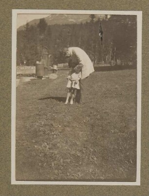 Hugo von Hofmannsthal mit seinem Sohn Raimund im Garten stehend, sich zum Kind hinunterbeugend