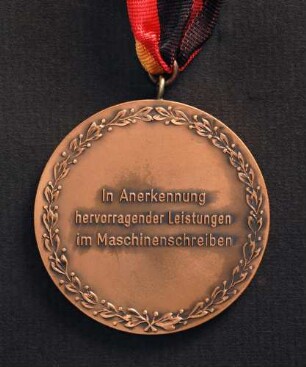 Bronzemedaille Deutsche Meisterschaften in Kurzschrift und Maschinenschreiben in Gießen 1977 am schwarz-rot-goldenen Band : Sammlung Deutscher Stenografenbund. Bronzemedaille Deutsche Meisterschaften in Kurzschrift und Maschinenschreiben in Gießen 1977 am schwarz-rot-goldenen Band. Messing, bronziert; Durchmesser 50 mm, Gewicht 50 g (1977; Deschler & Sohn, München). Dresden: SLUB R c 0526
