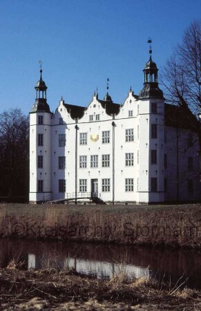 Schloss Ahrensburg: Ansicht von Südosten: Südfassade mit angrenzenden Türmen: an mittlerem Giebelhaus Sonnenuhr: Gartenportal, Gartenbrücke über inneren Schlossgraben: im Vordergrund äußerer Schlossgraben