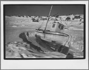 Fischerboot im Eis vor Wohnsiedlung