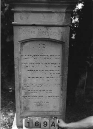 Grabstein 169 (Index: 100110651) Material: Sandstein Zustand: Giebel beschädigt, ehemals schwarz ausgelegt Schrift Maße HxBxT: 167x64x36 cm Beschreibung: Stele, Sockel profiliert, Giebel mit mehrfach geschwungenem Abschluß, Schriftfeld eingetieft mit Segmentbogenabschluß Symbolik: florale Motive: Grabstein 169A