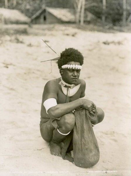 "Native of Malaita with forehead chain, arm and leg bracelets, holding a pouch"