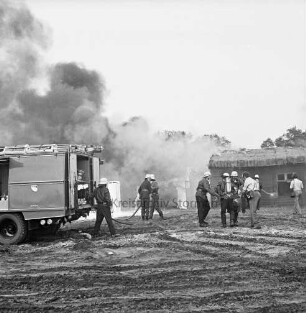 Stemwarde: Kreisfeuerwehrverbandstag: Löschübung: hinten Feuerwehrmänner beim Löschen von Tankstelle und Wohnhaus: links Löschwagen: davor Feuerwehrmänner beim Verlegen der Wasserschläuche