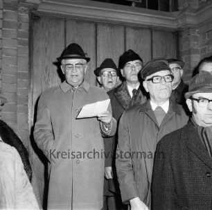 Kirchberg: Weihnachtskonzert vor der Kirche: Städtischer Musikkreis: Ansprache des Bürgerworthalters Georg Koch: rechts Mitglieder des Oldesloer Männerchores von 1844: hinten Kirchenportal: Abend: 23.12.1974