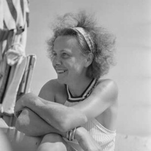 Frau mit Haarband sitzt am Strand