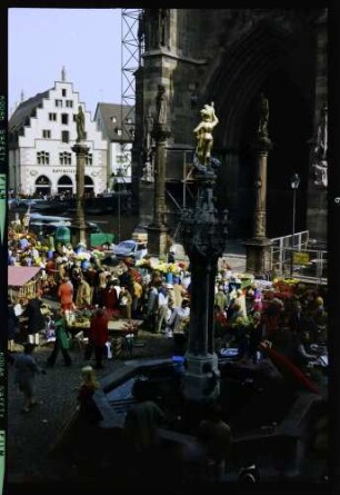 Freiburg: Münsterbrunnen von der Eisdiele, mit Markt und Kornhaus