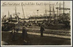 Am Hafen von Istanbul beim Abtransport einer Ladung Säcke durch mehrere Arbeiter, im Vordergrund Schienen, im Hintergrund zahlreiche Segelschiffe, Beginn des Baus der Bagdadbahn in der Türkei