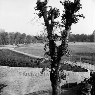 Stormarnhalle: Außenanlage vorne, dahinter Grünfläche und Sportplatz am Exer, links der Konrad-Adenauer-Ring: Blick nach Westen