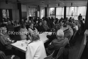 DRK-Ortsverein Reinfeld: Begegnungsstätte: Jahresversammlung: Mitglieder an Tischreihen: hinten Fensterfront, Fotowand und Schränke