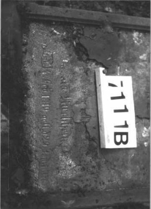 Grabstein 1111 (Index: 99899784) Material: Sandstein Zustand: stark verwittert Maße HxBxT: 153x63x14 cm Beschreibung: aufgesockelte Stele mit geschweiftem Bogenabschluss, Levitenkanne im Bogenfeld, umgestürzt, liegt Symbolik: Levitenkanne: Grabstein 7111B