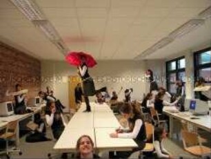 Inszenierte Szene im Computerraum einer Schule: Schülerin steht mit einem roten Schirm auf dem Tisch, dazu weitere "Klone" (Prämiertes Foto, Imaging-Special)