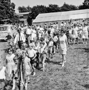 Kindervogelschießen: Festwiese: Festumzug: Klassen mit Blumenstöcken: rechts Lehrerinnen: hinten Zuschauer vor Festzelt: hinten links VW-Bus: dahinter Gebäude