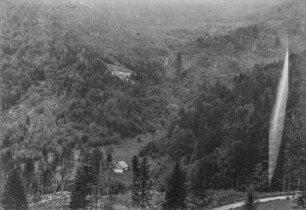 Berglandschaft : Blick auf Waldflächen an Berghängen, im Vordergrund eine Berghütte und eine Straße