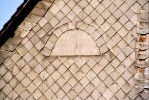 Detail einer Schieferwand, Halbkreis mit Inschrift (nicht lesbar)
