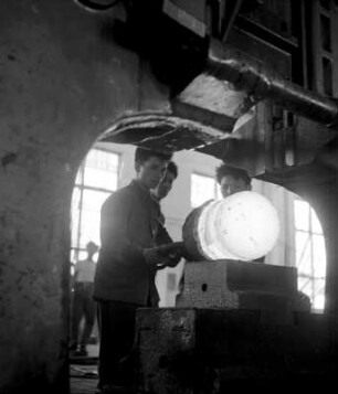 Arbeiter eines Stahlwerks an einer Schmiedepresse