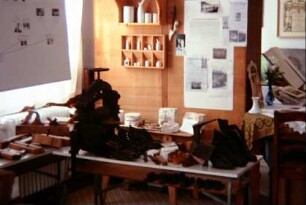 Heimatstube: alte Schuhmacherbank mit Schuhen, daneben Tischlerwerkzeug, hinten Porzellanformen und Porzellan
