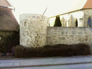 Ansicht von Südosten mit Rundturm (Schießscharten erhalten-Obergeschoß abgetragen) sowie anschließender Kirchhofmauer (Wehrgang im 18 Jh abgetragen)