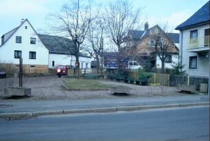 Dorfplatz mit drei Betonpflanzschalen und Bänken
