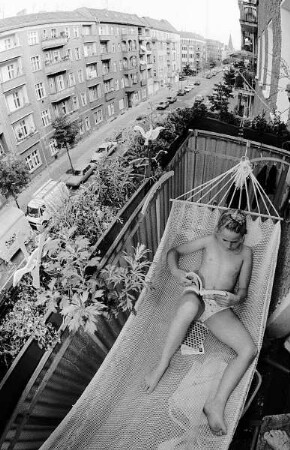 Ein Mädchen in der Hängematte auf einem Balkon