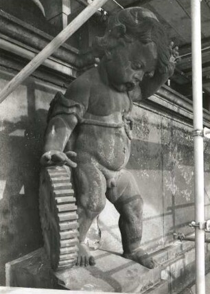 Putto mit Zahnrad : Putto mit Zahnrad. Sandstein (um 1905). Seitenansicht mit Gerüst. Dresden-Altstadt, Schloßplatz 1, Baustelle Ständehaus (Bauphase Substanzsicherung / Wiederaufbau Dach)
