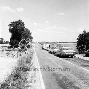 Straßenbau: B 75: Bauarbeiten am Straßenrand: rechts wartende Pkws: links Bagger: dahinter Bäume