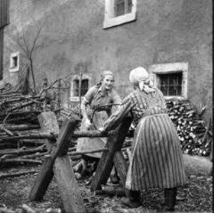 Arbeitsmaid des Reichsarbeitsdienstes und Bäuerin beim Holzsägen