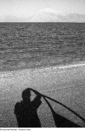 Schatten-Selbstbildnis des Fotografen vor Wasser und Bergen