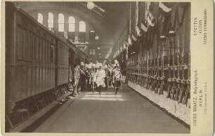 Empfang von König Umberto I. (Humbert) von Italien im Berliner Bahnhof, begleitet von Offizieren, salutierend beim Abschreiten einer das Gewehr präsentierende Reihe von Soldaten auf dem Bahnsteig in der Bahnhofshalle