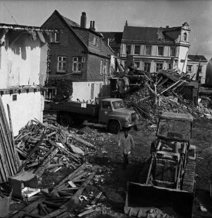 Firma Carl Hoffmann: Hindenburgstraße: Elektrohandel: Abriss des Firmengebäudes: Bauschutt mit Bretterhaufen: dazwischen Bagger, Lkw und Arbeiter: hinten links Wohn- und Geschäftshaus: hinten Mitte Wohn- und Geschäftshaus mit Drogerie Purnhagen: hinten rechts Rathaus