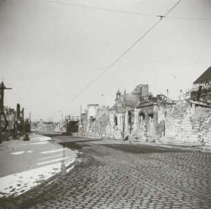Blick über Gebäudereste und gestapelte Steine gegen Ruine der Reformierten Kirche und Neues Rathaus
