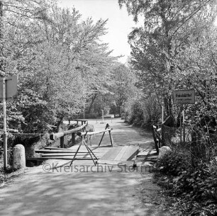 Lottbek: An der Lottbek: provisorisch ausgebesserte Holzbrücke über die Lottbek zwischen Hoisbüttel und Hamburg: darauf Mädchen mit Fahrrad: rechts Ortsschild von Hoisbüttel: dahinter Büsche und Bäume